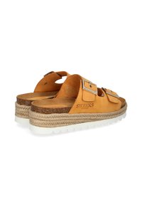Tan leather sandals with two adjustable straps, a textured cork footbed, and a woven espadrille-style sole with a white rubber base.