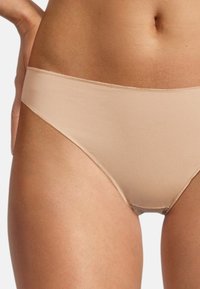 Slip in cotone beige con una texture liscia, design a vita media e una cintura ampia. I bordi senza cuciture creano un aspetto minimalista.