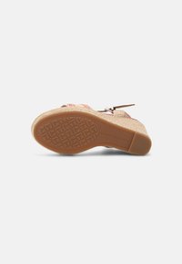 Semelle de sandale compensée avec grip texturé, talon tissé beige, bride de cheville ajustable et marquage visible "Tommy Hilfiger" sur la semelle en caoutchouc.