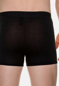 Svart boxerunderkläder gjorda av ett tunt, stretchigt material. Har en mjuk midja och en tajt passform med minimala synliga sömmar.