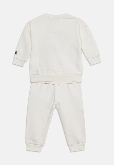 Ensemble blanc sweat-shirt à manches longues et pantalon pour tout-petits, avec poignets côtelés et petit texte noir sur la manche gauche.