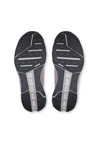 Semelles en caoutchouc noir de baskets avec des motifs de grip texturé et une bande blanche centrale. Le design comprend des carrés et des lignes en relief de différentes tailles.