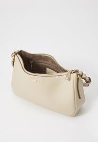 Sac à épaule en cuir beige avec des accessoires en or, fermeture à glissière, et une sangle détachable unique. L'intérieur présente une poche zippée et une texture lisse.
