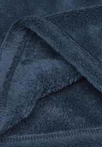 Coperta in pile blu navy con una superficie morbida e testurizzata e finitura pelosa. I bordi sono cuciti per garantirne la durata e un aspetto ordinato.