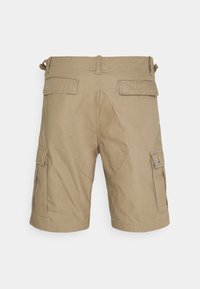 Shorts cargo beiges en tissu texturé, dotés de deux poches latérales et d'un écusson de logo, avec un détail de couture courbée à l'arrière.