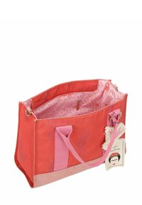 Sac fourre-tout en toile rouge avec des accents roses, doté d'une ouverture supérieure, d'une poche intérieure et d'une étiquette décorative représentant un visage.