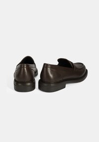 Dunkelbraune Lederloafer mit einer strukturierten Oberfläche, abgerundeten Zehen und subtilen Stickdetails. Niedrige, strapazierfähige schwarze Gummisohlen.