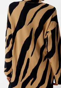 Cardigan a maniche lunghe in maglia con sfondo beige e strisce nere a motivo tigre, vestibilità comoda e colletto e polsini ribbed.