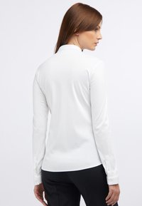 Langärmliges, weißes Hemd mit tailliertem Design, weichem Material und Knopfdetails an den Ärmeln. Es hat einen klassischen Kragen und einen glatten Stoff.