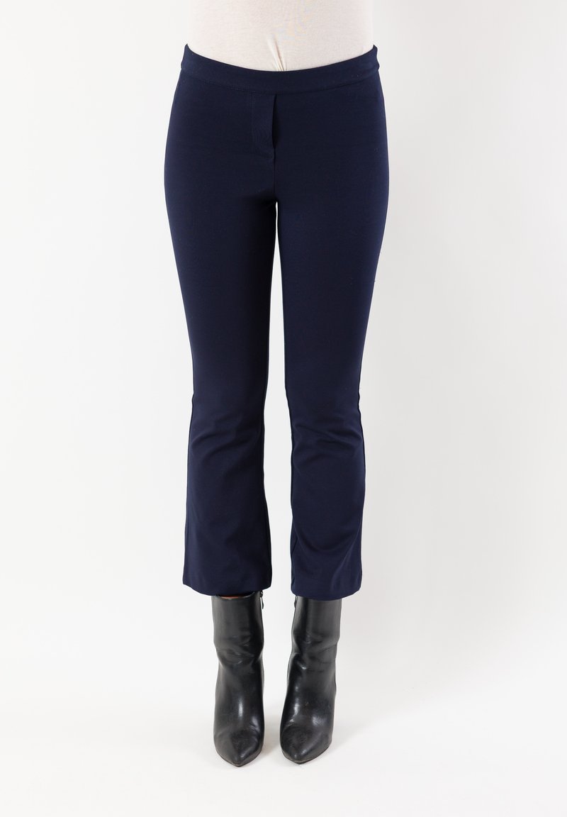 Pantaloni blu navy tagliati sopra la caviglia con una cintura larga, texture liscia e dettaglio cucito sul davanti; abbinati a stivaletti neri con tacco.