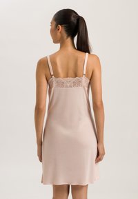 Abito slip rosa pallido con spalline regolabili, caratterizzato da un bordino in pizzo nella parte superiore. Tessuto morbido con un orlo a lunghezza ginocchio e vestibilità rilassata.
