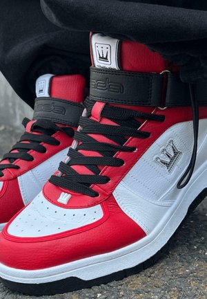 High-top sneakers feature a red and white leather upper with black accents, black laces, and a crowned logo on the ankle.