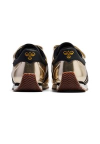 Schwarze und metallisch goldene Sneakers mit einer strukturierten Oberseite, ausgestattet mit einer gemusterten Sohle und einem markanten gelben Bienenlogo an der Ferse.