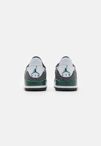 Crno-bijele tenisice s zelenim akcentima, s teksturiranim sivim petom, Air brandom i prepoznatljivim Jordan logom.