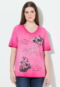 Camiseta de cuello en V en color rosa con gráficos florales en negro y texto escrito a mano. Mangas cortas con un efecto de tinte degradado, material de algodón suave.