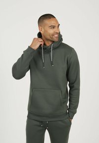 Sweat à capuche vert foncé en tissu lisse, doté d'une poche kangourou, de cordons de serrage ajustables et de poignets côtelés aux manches et à l'ourlet.