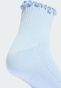 Svetlomodrá rebrovaná ponožka s volánkovým lemom. Vyrobená z mäkkého materiálu, s jemnou textúrou a tesným strihom okolo členku.