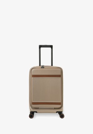 Valise rigide beige à rainures verticales, avec des accents marron, quatre roues pivotantes et une poignée télescopique noire étendue.