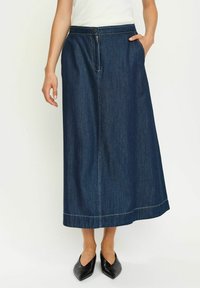 Denim maksi krilo v temno modri barvi z oprijetim pasom, zapiranjem na gumbe, stranskimi žepi in belim šivanjem. Nosen s črnimi točkastimi balerinkami.