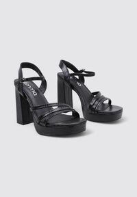 Sandalias de plataforma negras con múltiples tiras anchas y un tacón robusto. Fabricadas en un material texturizado con un acabado suave. Cierre de hebilla.