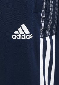 Marina atletiska shorts i en strukturerad tyg, med vit Adidas-logotyp och tre vertikala vita ränder på sidopanelen.