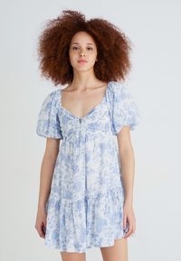 Vestido curto floral em azul claro e branco, feito de um tecido suave, com mangas bufantes, decote quadrado e bainha em camadas.