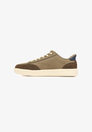 Lage casual sneaker in beige en bruin met witte zool, vetersluiting en donkerblauwe hielaccent.