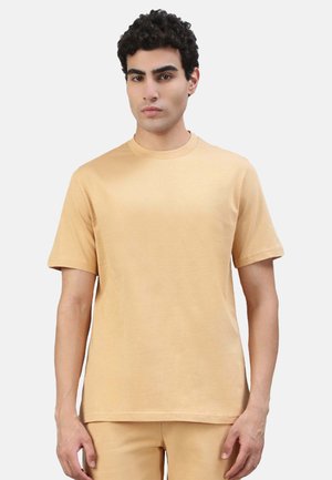 T-Shirt mit kurzen Ärmeln und rundem Ausschnitt in einem hellbeigen Farbton. Hergestellt aus weichem Stoff mit glatter Textur, zeichnet sich durch schlichte Linien und einen lässigen Schnitt aus.