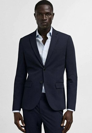 Navy blazer with two buttons, notched lapels, and front pockets, worn over a light blue striped dress shirt. Smooth fabric texture.