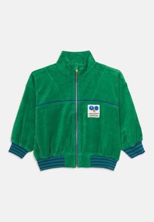 Jachetă din fleece verde cu manșete și talie cu dungi albastre, fermoar frontal complet și un mic patch cu două palete de tenis de masă și text pe piept.