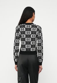 Czarny i biały sweter z wzorem w sploty, z długimi rękawami i ściągaczami. Projekt charakteryzuje się powtarzającym się motywem graficznym oraz dopasowanym talią.