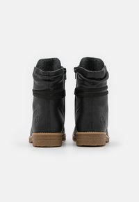 Bottes de cheville en cuir noir avec une doublure grise texturée, deux zips latéraux, des accents en élasthanne et une semelle en caoutchouc beige pour l'adhérence.