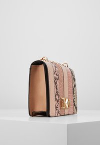 Borsa rettangolare di colore rosa chiaro con stampa serpente e accenti glitter. Caratterizzata da una chiusura in metallo dorato e una tracolla a catena. Texture liscia.
