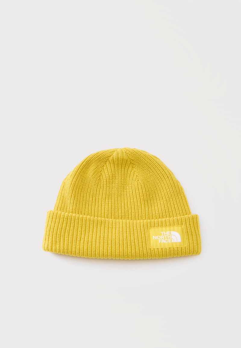 Bonnet en maille jaune avec bord replié, présentant un patch logo North Face rectangulaire blanc sur un fond clair uni.
