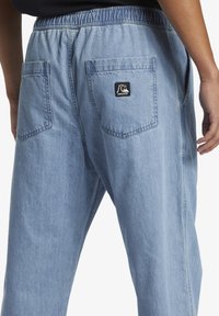 Svijetloplave traperice s elastičnom waistbandom, dva stražnja džepa i mali logotip na desnom džepu. Glatka tekstura.