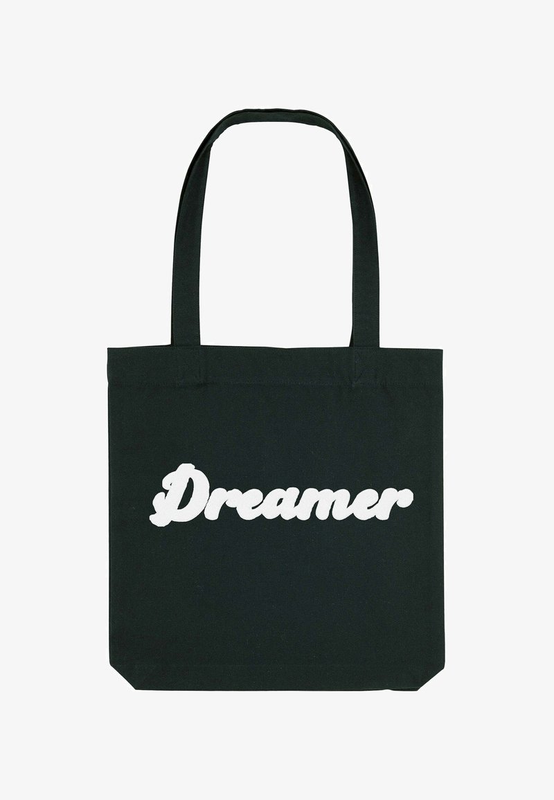 Fekete pamut vászontáska, amelyen nagy, fehér, ívelt betűkkel olvasható a "Dreamer" szó. A táska két strapabíró fogantyúval rendelkezik.