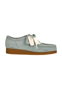 Wildleder-Mokassinschuhe in zartem Blau mit einer dicken braunen Gummisohle, versehen mit dekorativen weißen Schnürsenkeln und Nähdetails.