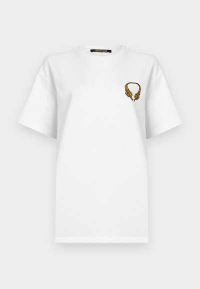 Λευκό κοντομάνικο μπλουζάκι με μικρό κεντητό σχέδιο δύο καθρεπτιζόμενων κεφαλών τίγρης που σχηματίζουν κύκλο στο πάνω αριστερό στήθος.