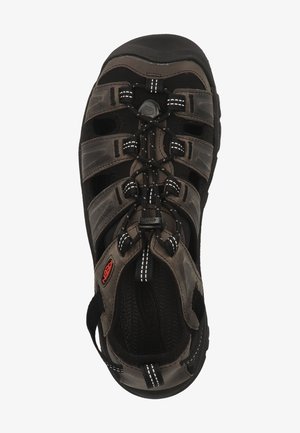 Sandalia exterior marrón y negra con correas robustas, suela de goma texturizada y un sistema de lazada ajustable para un ajuste seguro.