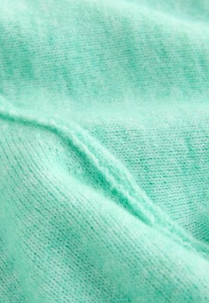 Mintgrønt strikket stof med en glat tekstur, der har et subtilt mønster og synlige syningsdetaljer langs kanterne.