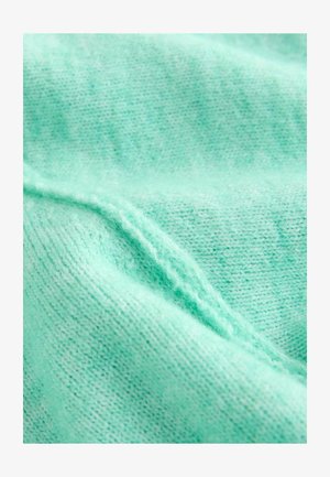 Mintgrønt strikket stof med en glat tekstur, der har et subtilt mønster og synlige syningsdetaljer langs kanterne.