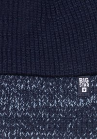 Dzianinowa czapka w ciemnym granacie z prążkowaną teksturą na górze oraz wzorzystą sekcją poniżej, z małą metką "BIG STAR".