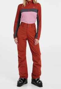 Rote Skihosen mit hoher Taille, Knopf- und Reißverschluss, kombiniert mit einem langärmeligen Oberteil in Rot, Rosa und Grau. Das Oberteil verfügt über einen Viertelreißverschluss.