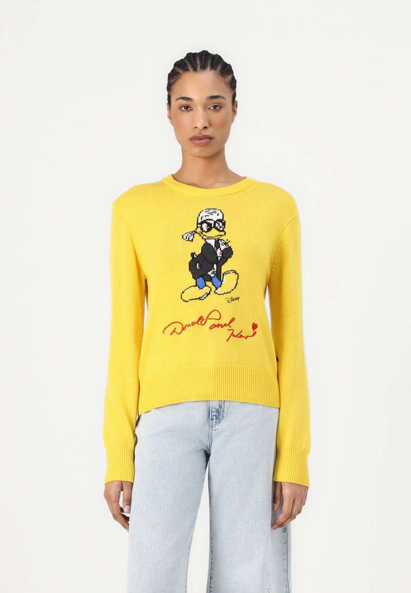 Pull en maille jaune avec un graphique d'un canard de dessin animé portant des lunettes, avec un texte rouge en dessous. Manches longues et col rond.