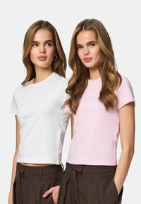 Deux t-shirts à manches courtes, l'un blanc et l'autre rose pastel, fabriqués en coton doux, avec un col rond et une coupe ajustée.