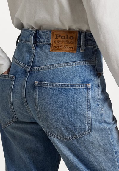 Ljusblå jeans i denim med en läderetikett från Polo. Har bakfickor, rak benform och en lätt urblekt textur.