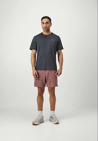 T-shirt de sport gris foncé avec un motif texturé, associé à un short rose. Tissu léger et chaussures de course avec des accents argentés.