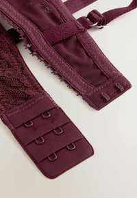 Burgundy rintaliivi, jossa on pitsikoristeet ja teksturoitu pinta. Varusteena säädettävät hakaset ja useita hakaset-silmukkasulkuja istuvuuden säätämiseksi.