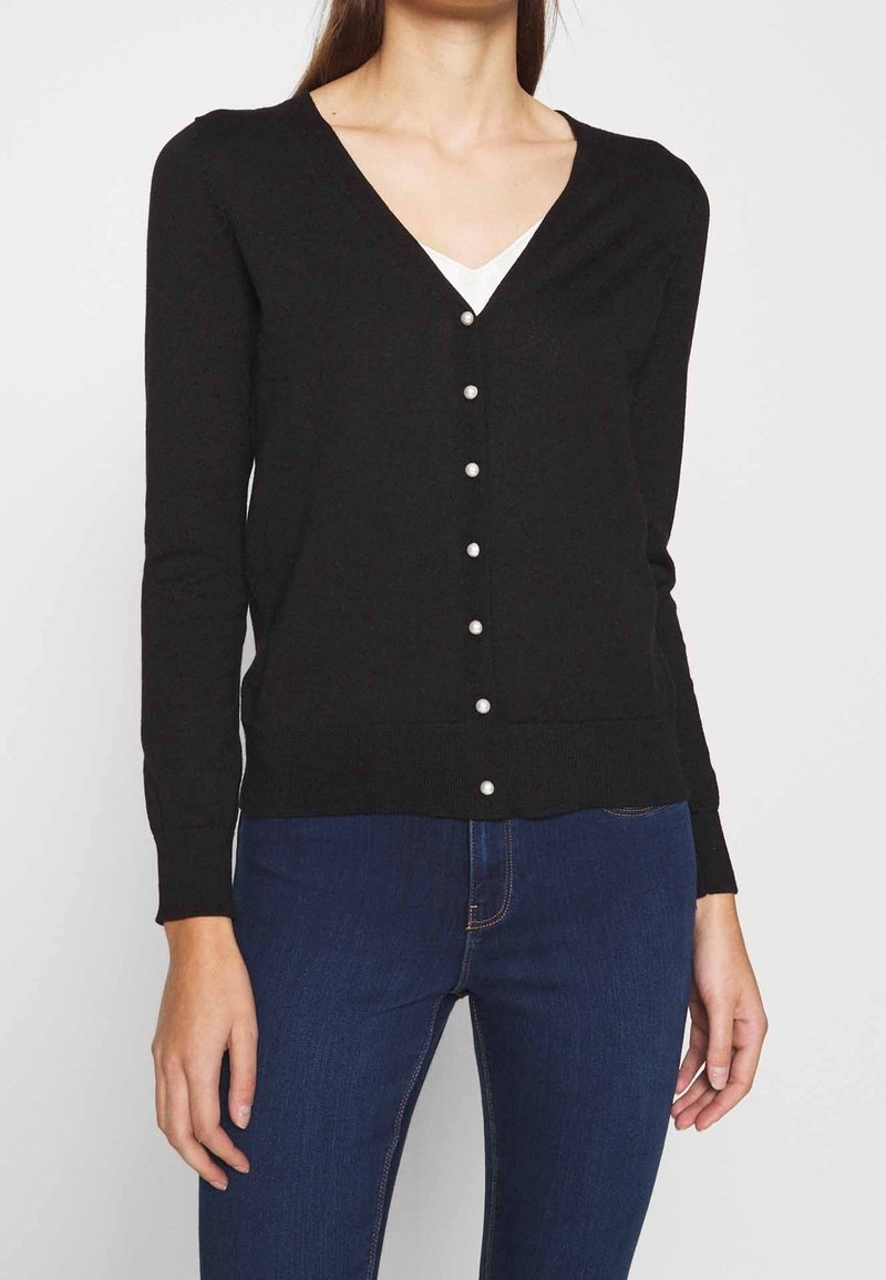 Svart cardigan i mjuk stickad tyg med V-ringning och sex pärlknappar fram; figurnära design med långa ärmar.