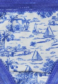 Blau-weißer Stoff mit Mustern von Segelbooten, tropischen Bäumen und Häusern, verziert mit einem lila Spitzenrand, der einen strukturierten Look erzeugt.